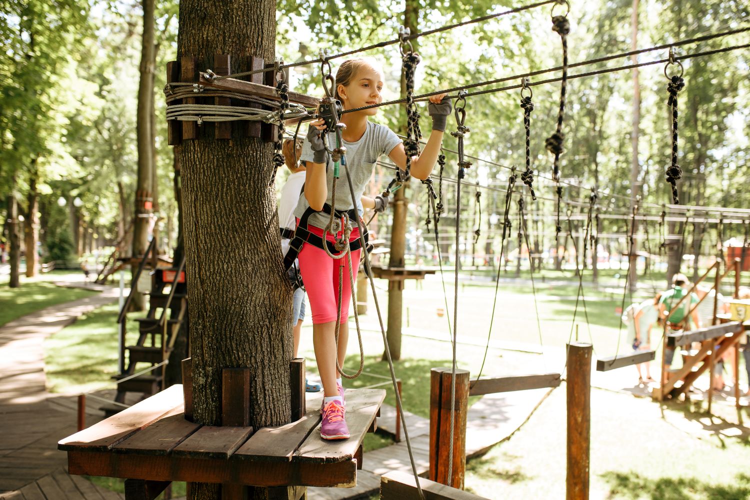 Enfant équipée d'un baudrier sur un parcours d'accrobranche dans les arbres